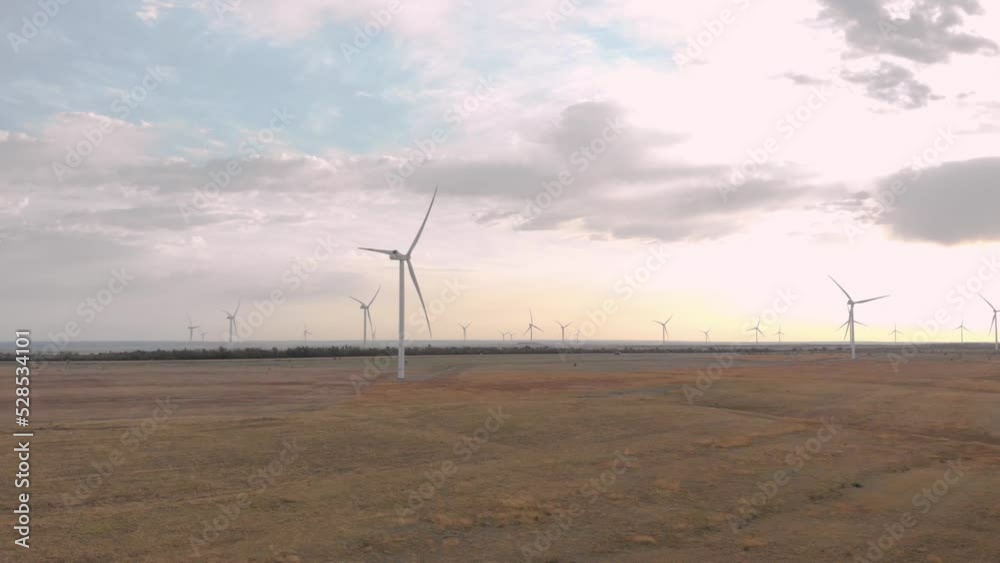 Large wind generators of electricity. Be in the field. White blades. Wind energy. Sunrise. Farm lands. Alternative energy. Eco-friendly industry. Windy climate. Shooting from the air. Large wind generators of electricity. Be in the field. White blades. Wind energy. Sunrise. Farm lands. Alternative energy. Eco-friendly industry. Windy climate. Shooting from the air.