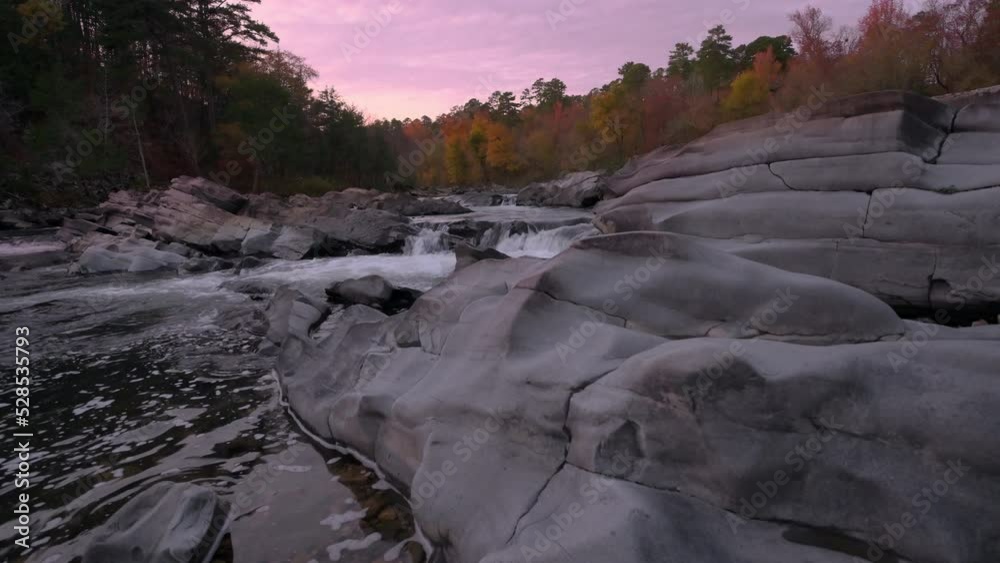 Sunset over fall forest with Cossatot Falls cascading river in foreground from an Arkansas State Park Sunset over fall forest with Cossatot Falls cascading river in foreground from an Arkansas State Park