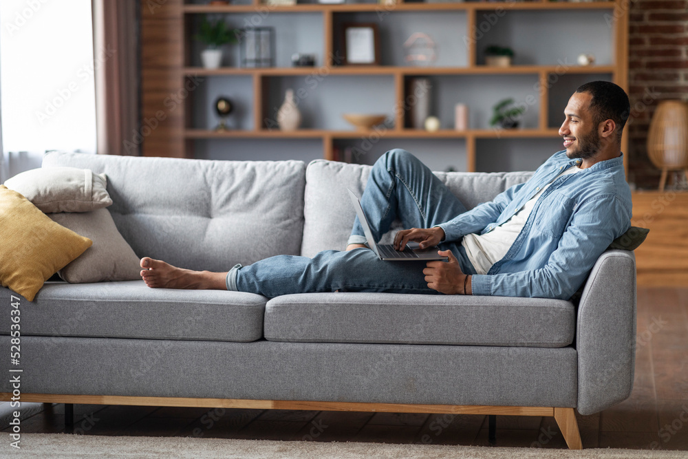 Handsome Black Man With Laptop Relaxing On Couch In Living Room Handsome Black Man With Laptop Relaxing On Couch In Living Room