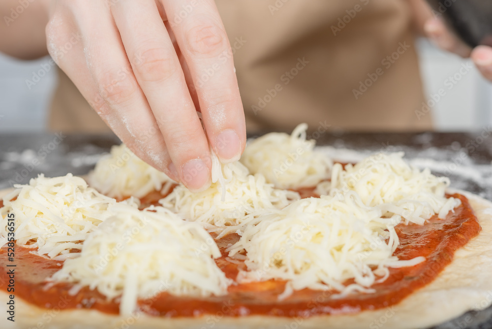 A woman prepares Margherita pizza in her kitchen. A woman prepares Margherita pizza in her kitchen.