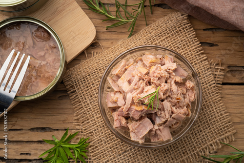 Canned tuna in brine in glass bowl on wooden table.Top view