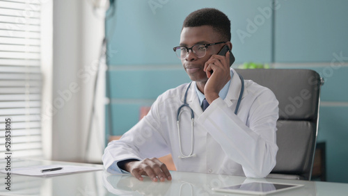 Young African Doctor Talking on Phone in Office