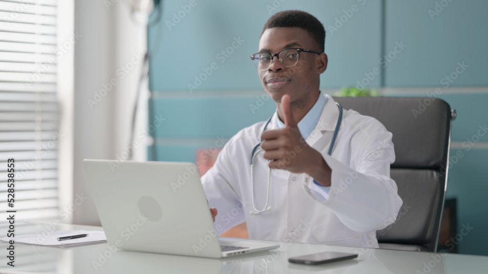 Young African Doctor Showing Thumbs Up Sign While using Laptop in Office