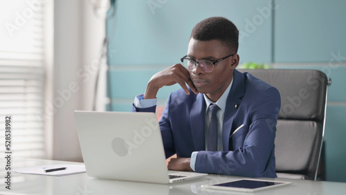 Wallpaper Mural Young African Businessman Thinking while Working on Laptop in Office Torontodigital.ca