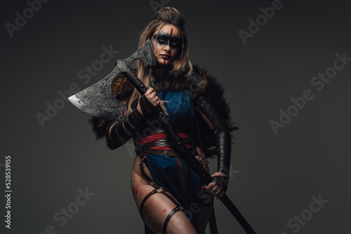 Shot of warrior woman with make up dressed in attire and fur looking at camera.