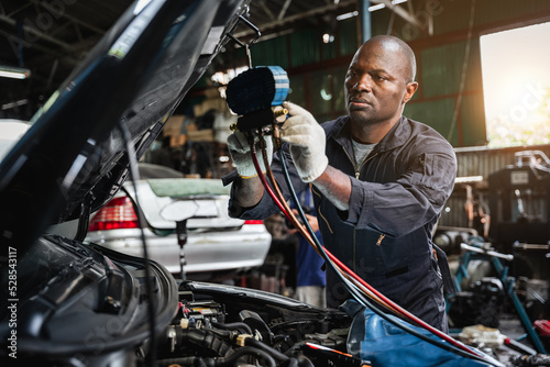 In the garage, mechanics examine and inspect the refrigerant before filling the car's air conditioner with it.