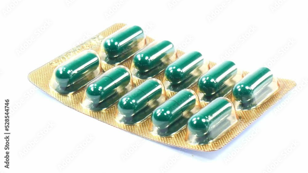 Close up one green pill pack isolated on white background.Slow motion footage.Macro vdo and selection focus. Close up one green pill pack isolated on white background.Slow motion footage.Macro vdo and selection focus.