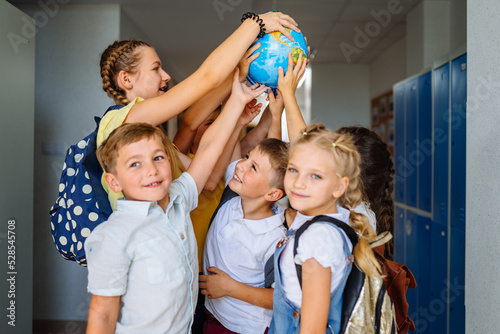 Schilderij op canvas Different age team of children playing with globe in hallway at school