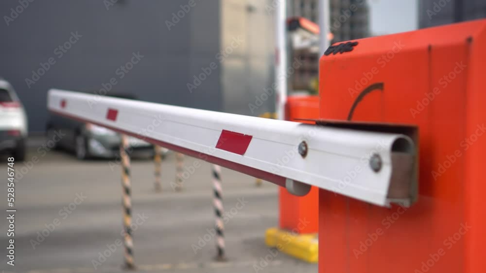 Barrier is raised and car enters parking lot. Security system for access to building - with paid cabin, and video surveillance system. Barrier on car parking. Automatic security of territory of buildi