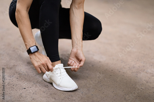 Cropped shot of woman tying shoelaces before running outdoors