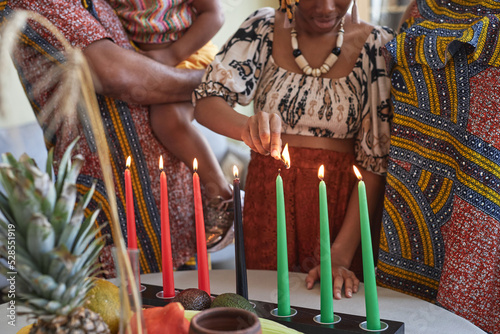 Close-up of African family of four in national costumes burning all seven candles for Kwanzaa holiday photo