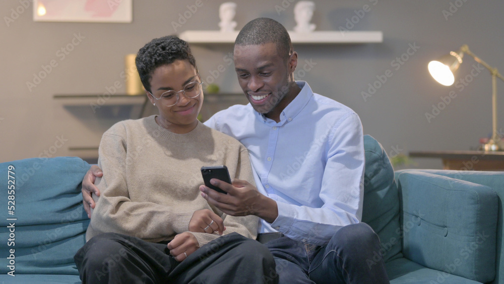 Couple using Smartphone While Sitting on Sofa Couple using Smartphone While Sitting on Sofa
