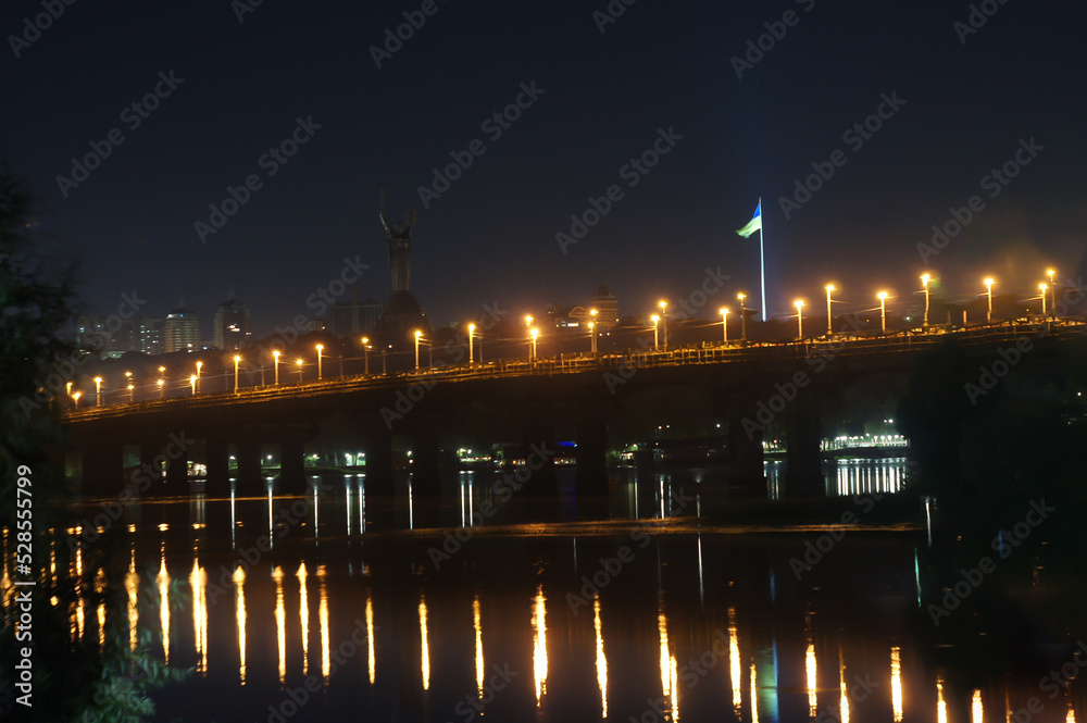 KYIV, UKRAINE - SEPTEMBER 03, 2022. Beautiful view of Kiev, the capital of Ukraine. Night view across the Dnieper River. The lights of the city at night are reflected in the river