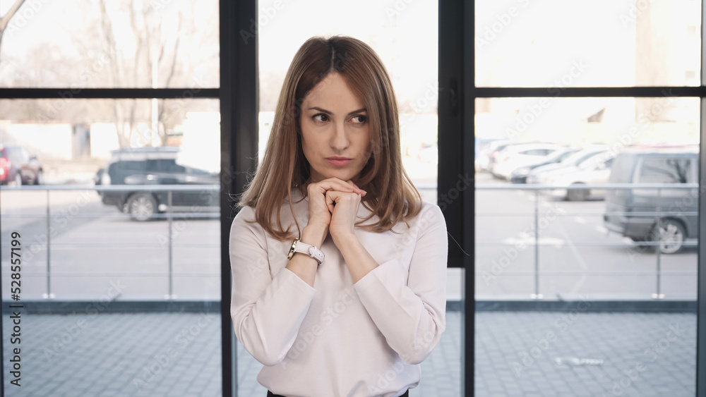 worried woman holding hands near face and looking away while waiting for job interview. worried woman holding hands near face and looking away while waiting for job interview.