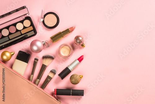 Make up products at pink background with cosmetic bag. Eye shadow, lipstick, powder, brushes and more for professional make up. Flat lay image with copy space.