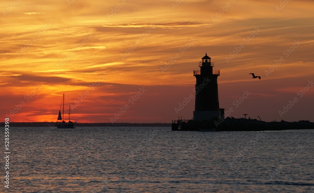 Silhouette of lighthouse and a yacht during sunset near Cape Henlopen State Park, Lewes, DE