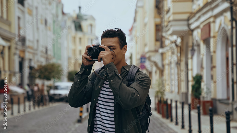 Bi-racial tourist taking photo on film camera on urban european street. Bi-racial tourist taking photo on film camera on urban european street.