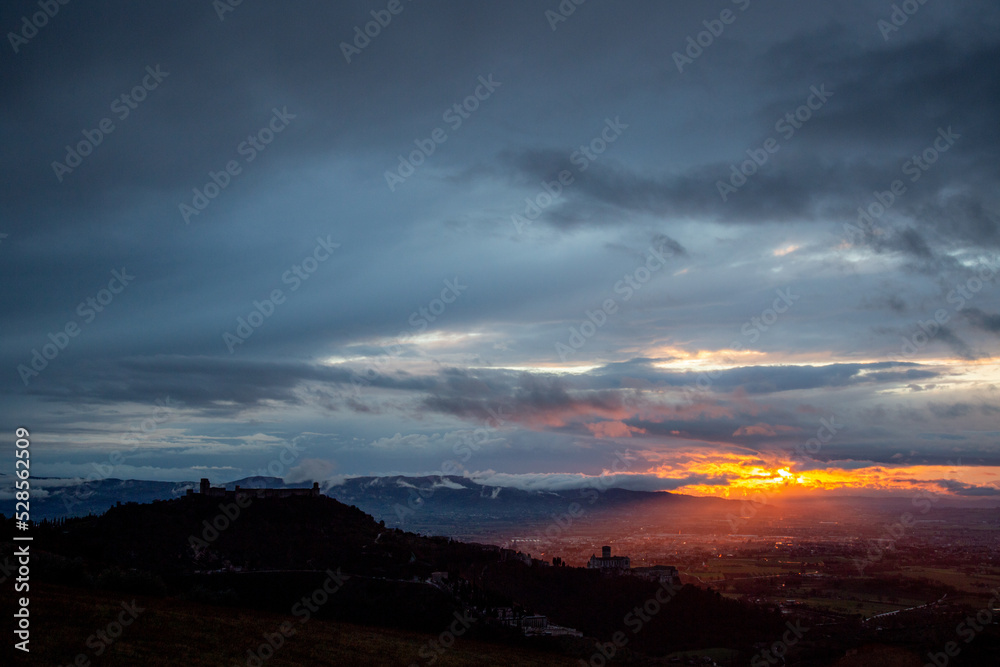 Beautiful view of Assisi town ,mbria, Italy at set, with moody clouds in the sky