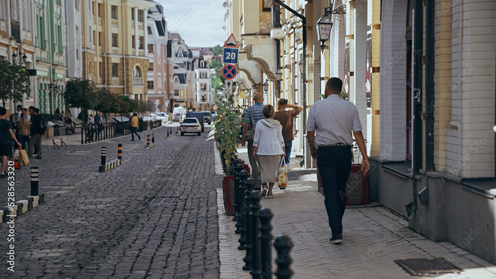 KYIV, UKRAINE - JULY 9, 2019: People walking near building on european street.