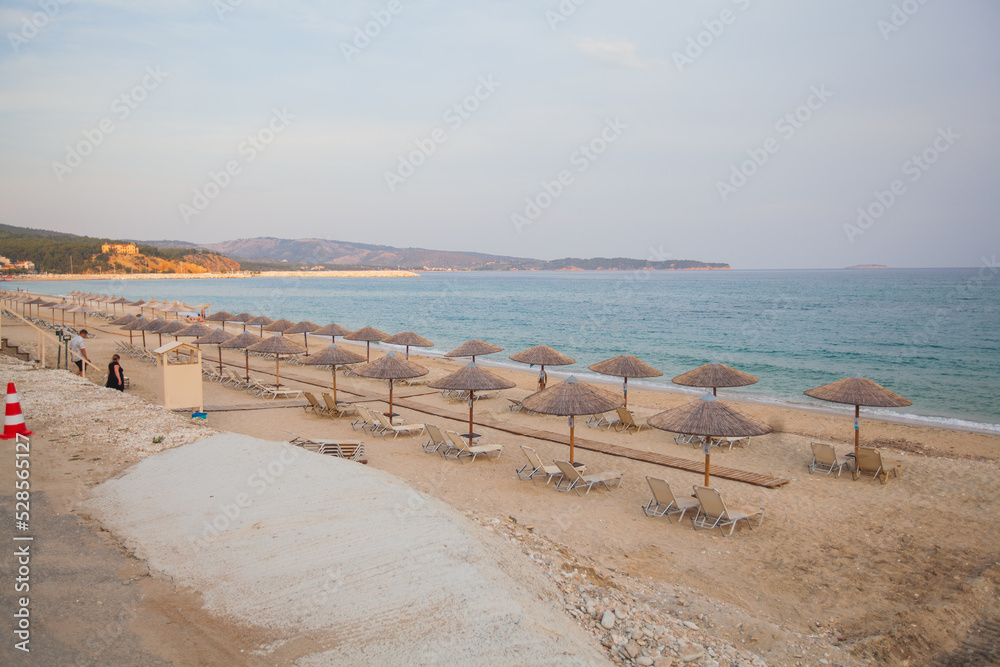 Empty organized sand beach with sunbeds and sunshade at sunset light. Beautiful view of seascape. Empty organized sand beach with sunbeds and sunshade at sunset light. Beautiful view of seascape.
