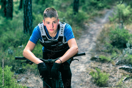 Teenager in forest with downhill bike.
