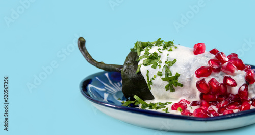 Banner de Chile en Nogada sobre plato de talavera azul en fondo azul claro,  comida mexicana.  photo