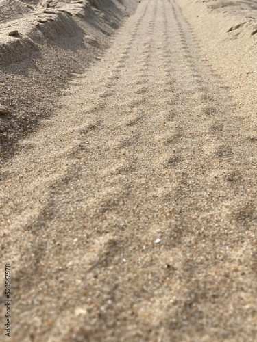 In the sand are grooves of a tire track