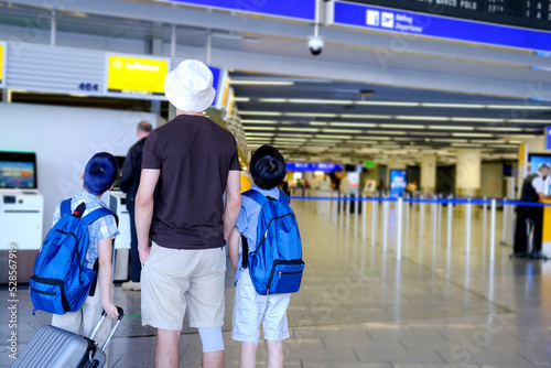 man and two children with backpacks and suitcase, Travelers standing in lobby of beautiful modern european Frankfurt airport, concept travel, voyage, air trip, do not miss your flight