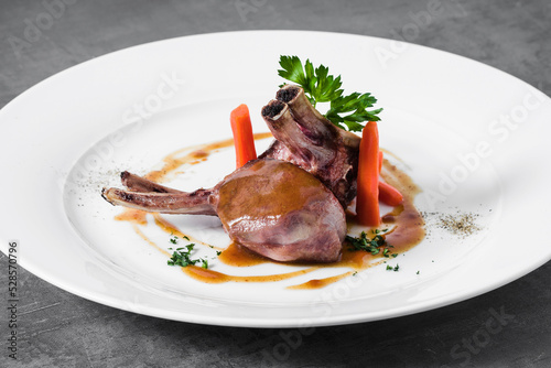 lamb in sauce with baby carrots on a plate. a dish in a restaurant on a dark background