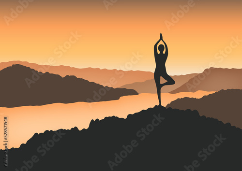 A woman in yoga tree pose in the mountain at sunrise.