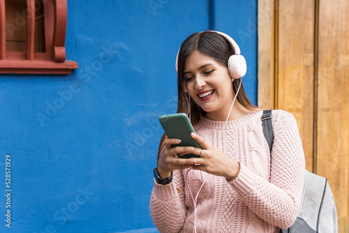 girl writing and listening to music on cell phone on blue background