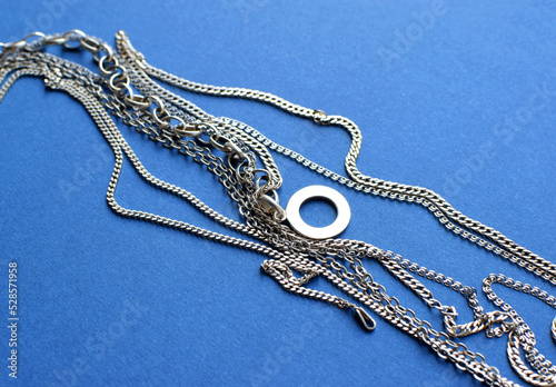 Different silver chains lie on a blue background. Jewelry for women and men