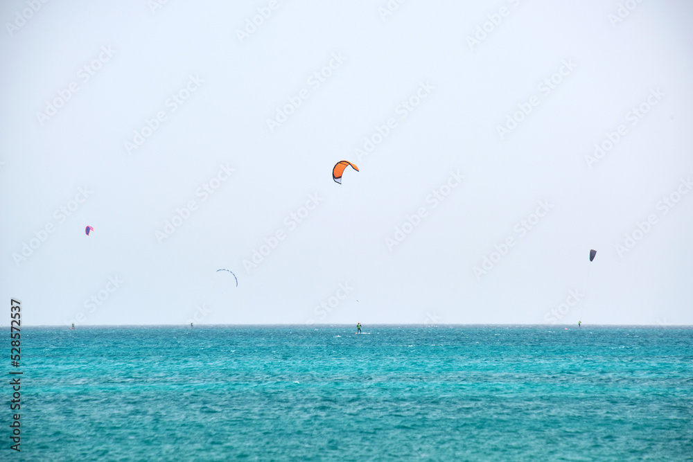 People sportsmen windsurfing and kite surfing in blue ocean water. Summer extreme exotic sport concept People sportsmen windsurfing and kite surfing in blue ocean water. Summer extreme exotic sport concept
