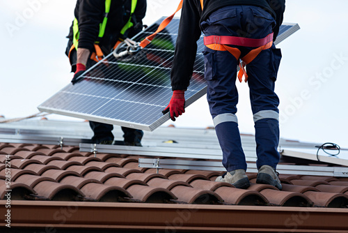 Dos técnicos instalando placas solares en una vivienda.