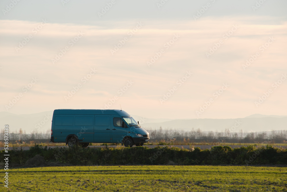Small cargo van driving on highway hauling goods. Delivery transportation and logistics concept