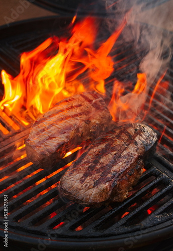 BBQ dry aged wagyu roast beef steak grilled as close-up on a charcoal grill with fire and smoke