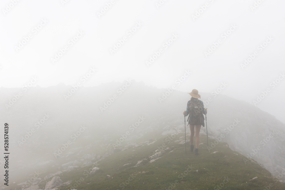 Hiker moving trough a Cloud Mist on top of a Mountain