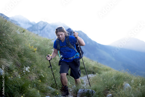 Mature Man Hiker Ascending on a Mountain Trail in Early Morning