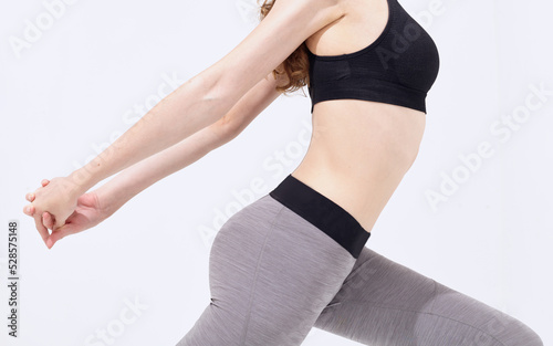 Beautiful young woman dressed in a gray sports uniform, posing in the studio on a gray background.Advertising sportswear and yoga wear. Healthy lifestyle, sport