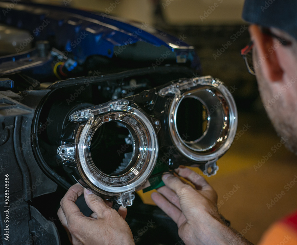 Car headlight in repair closeup. The car mechanic installs the lens in