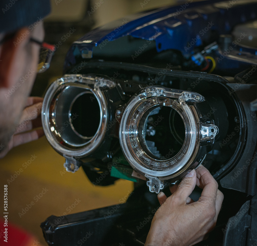 Car headlight in repair closeup. The car mechanic installs the lens in