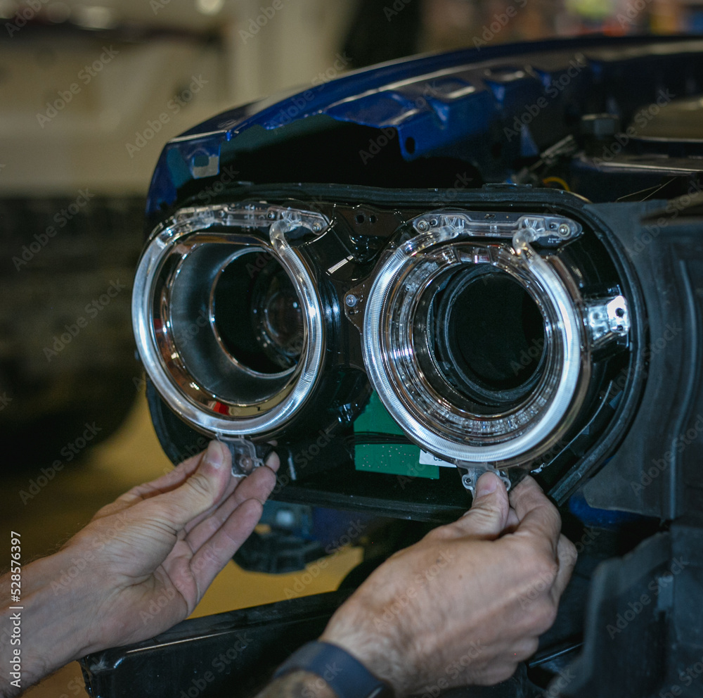 Car headlight in repair closeup. The car mechanic installs the lens in