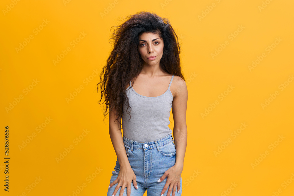 Portrait of young angry curly Latin woman feeling upset and depressed, looking at camera. Worried arab lady with serious concerned facial expression and sorrow emotion isolated on pink background Portrait of young angry curly Latin woman feeling upset and depressed, looking at camera. Worried arab lady with serious concerned facial expression and sorrow emotion isolated on pink background
