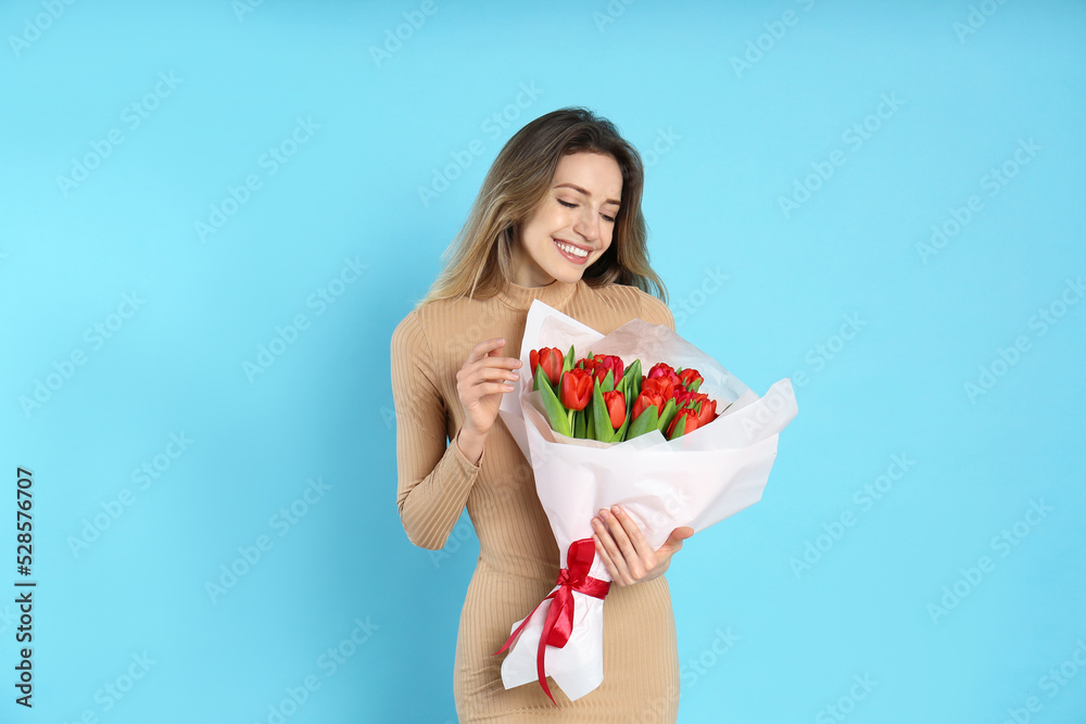 Happy woman with red tulip bouquet on light blue background. 8th of March celebration Happy woman with red tulip bouquet on light blue background. 8th of March celebration