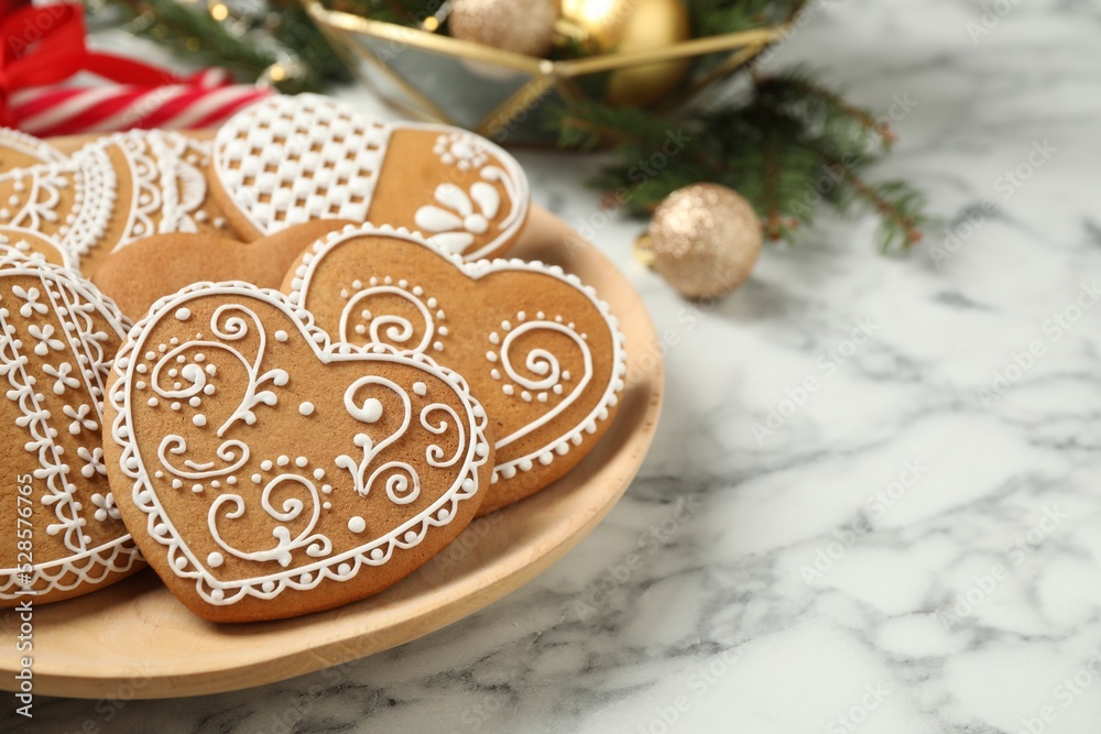 Tasty heart shaped gingerbread cookies on white marble table, closeup. Space for text