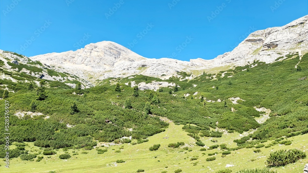 Val Badia, Italy-July 18, 2022: The italian Dolomites behind the small village of Corvara in summer days with beaitiful blue sky in the background. Green nature in the middle of the rocks. Val Badia, Italy-July 18, 2022: The italian Dolomites behind the small village of Corvara in summer days with beaitiful blue sky in the background. Green nature in the middle of the rocks.