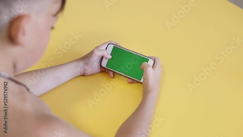 Child Using Phone With Green Mock-up. Surfing Internet Watching Content Videos Blogs Learning. boy Playing Video Games. chroma key for copy space. Slow motion.