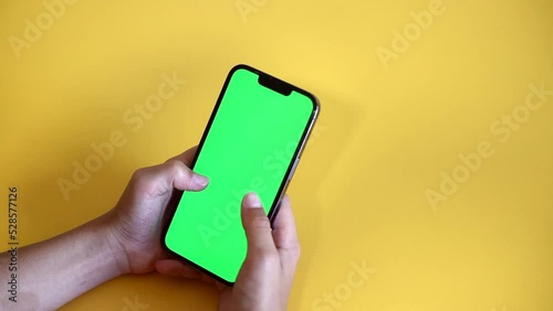 Chroma key mock-up on smartphone in hand. teenage boy use phone with green screen layout, color key, Watch content, play game. Use green screen for copy space closeup. Slow motion.