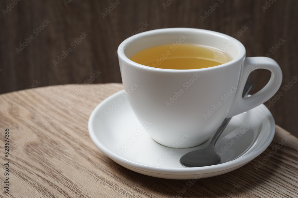 Cup of aromatic buckwheat tea and spoon on wooden table