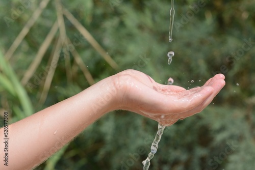 Pouring water into kid`s hand outdoors, closeup